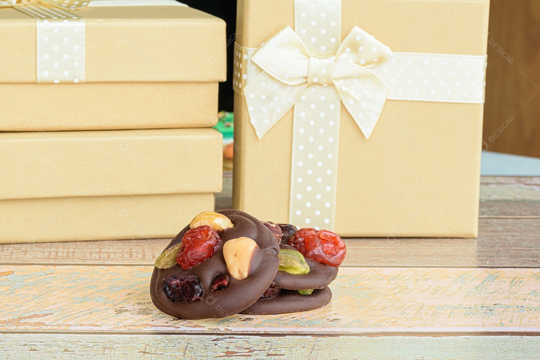 Três biscoitos de chocolate com nozes. Pequenas caixas de presente douradas