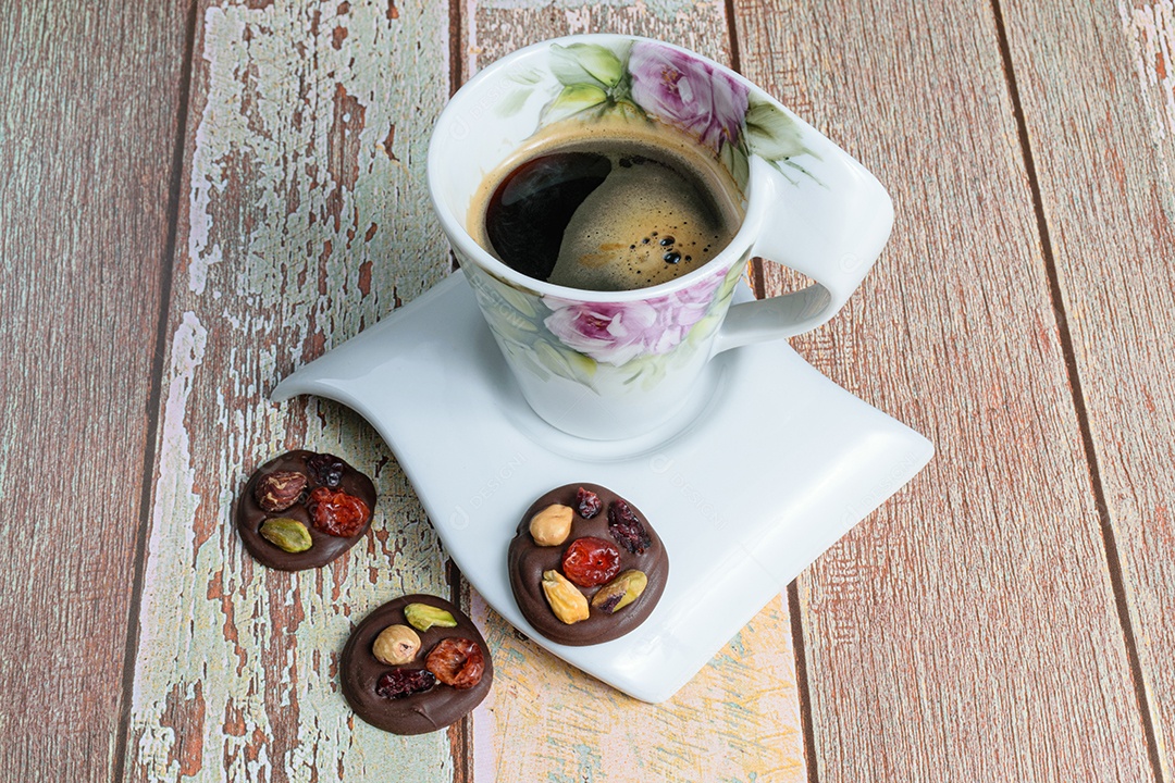 Três pequenos biscoitos de chocolate com nozes, ao lado de uma xícara de café