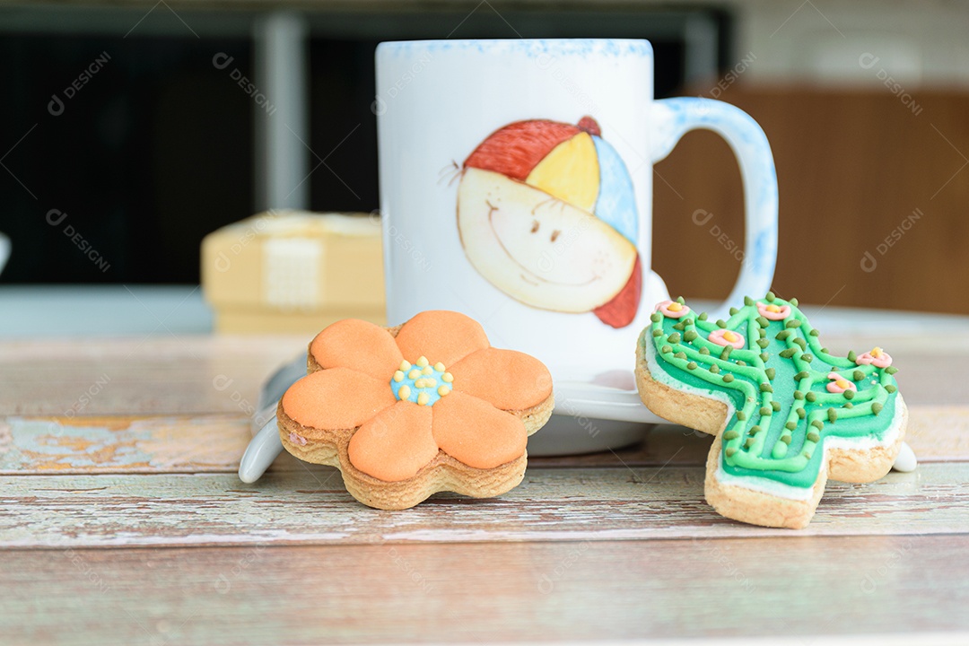 Close-up de dois cookies com forma variada ao lado de uma pequena caneca