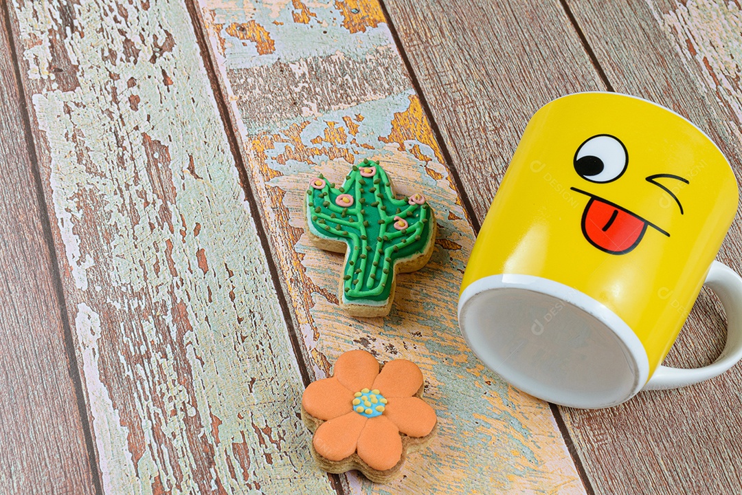 Biscoitos e cactos em forma de flor, ao lado de uma caneca amarela deitada