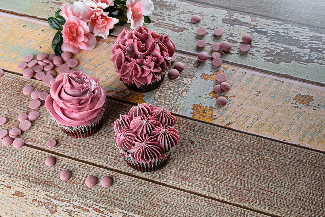 Três cupcakes de chocolate com creme de manteiga rosa