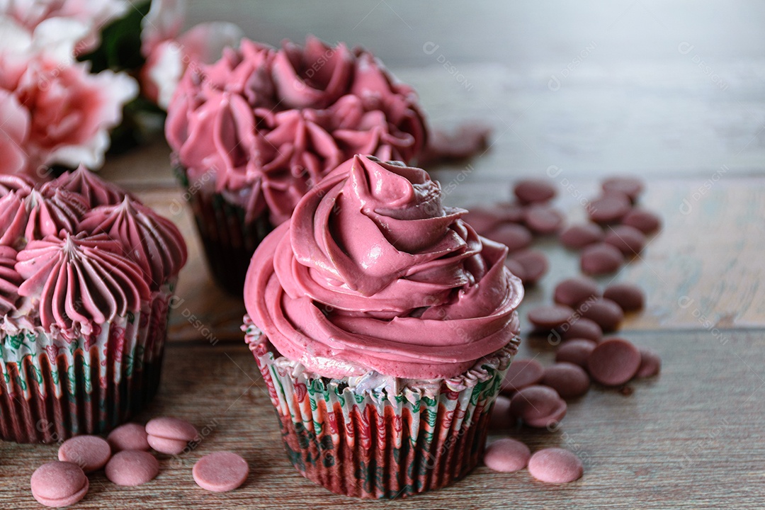 Closeup de três cupcakes de chocolate com creme de manteiga rosa