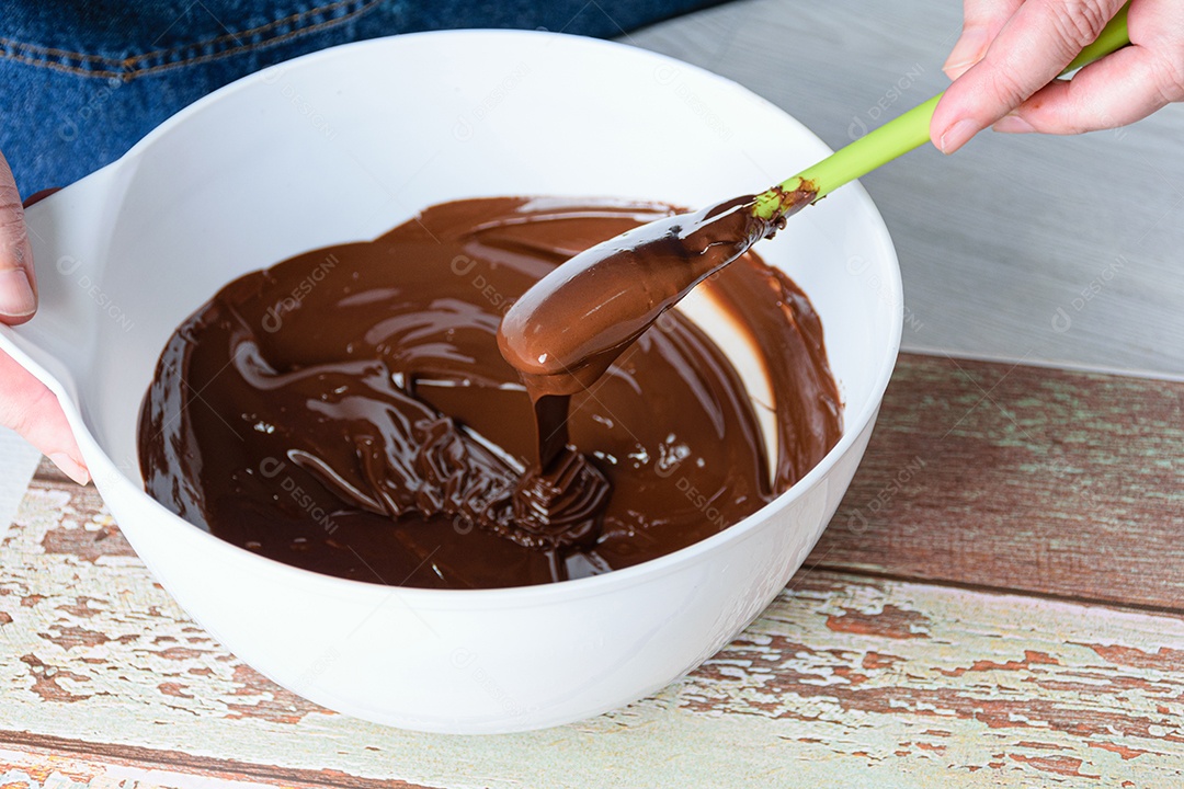 Confeiteiro temperando o chocolate com uma espátula em uma tigela branca
