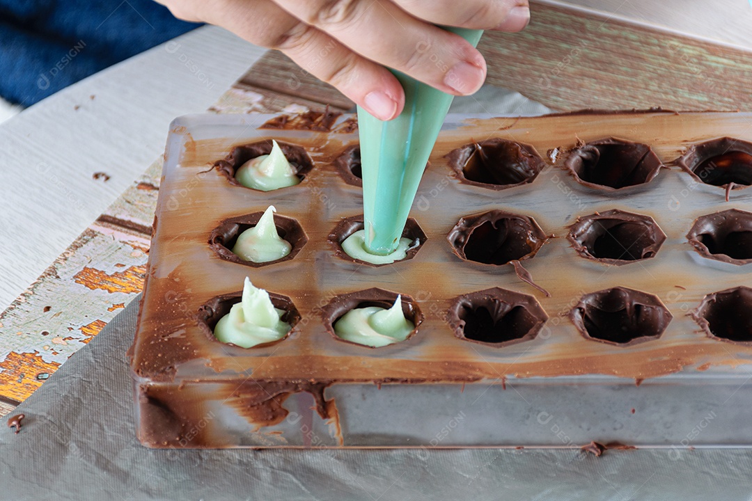 Confeiteiro usando um bico de confeiteiro para rechear bombons de chocolate