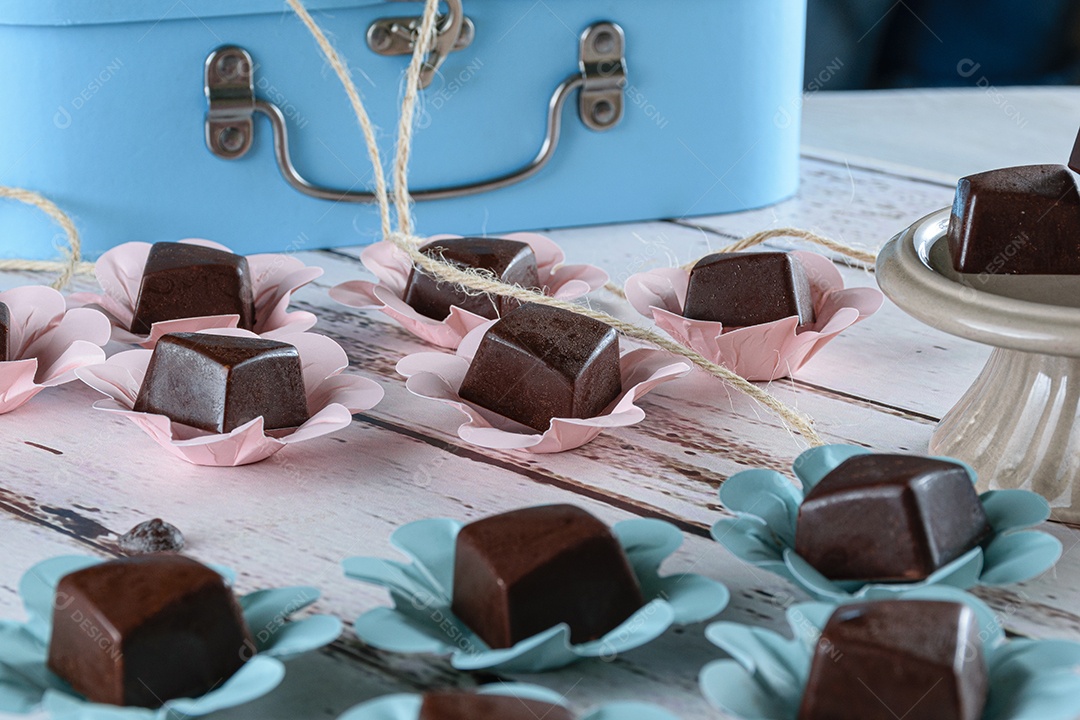 Bombons de chocolate em uma mesa branca e uma mala azul