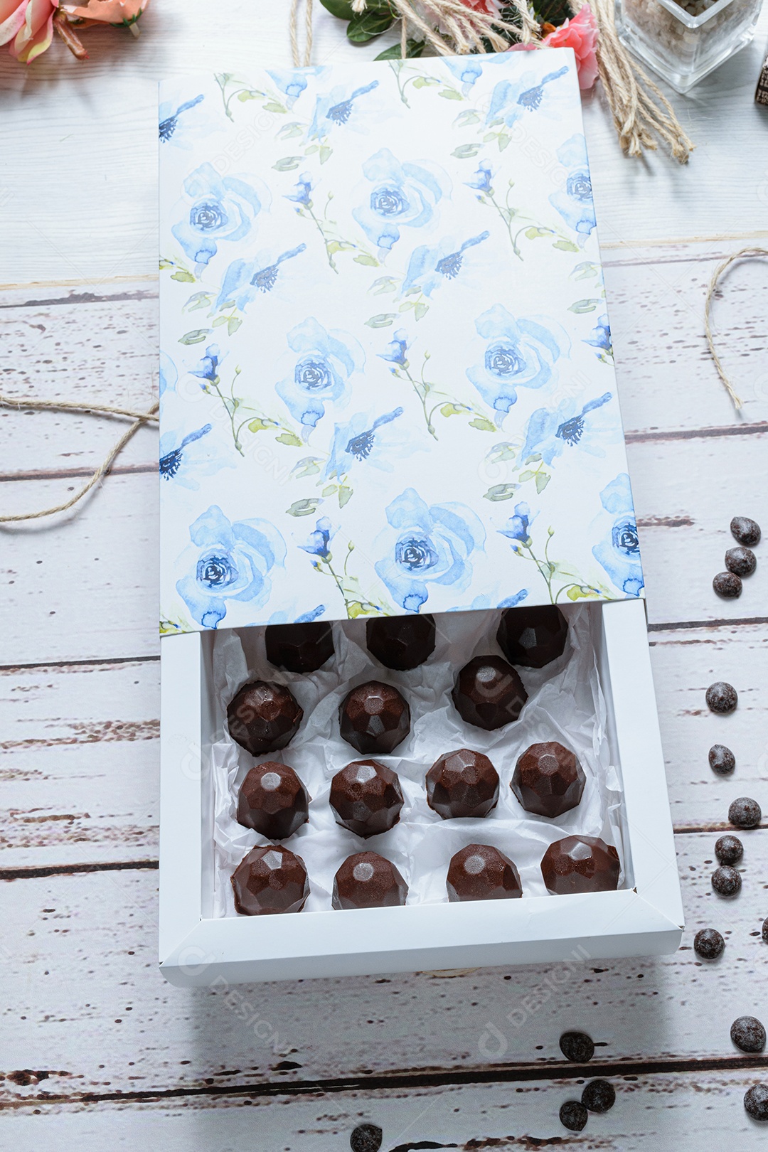 Caixa com chocolates em uma mesa branca, ao lado de corda de barbante