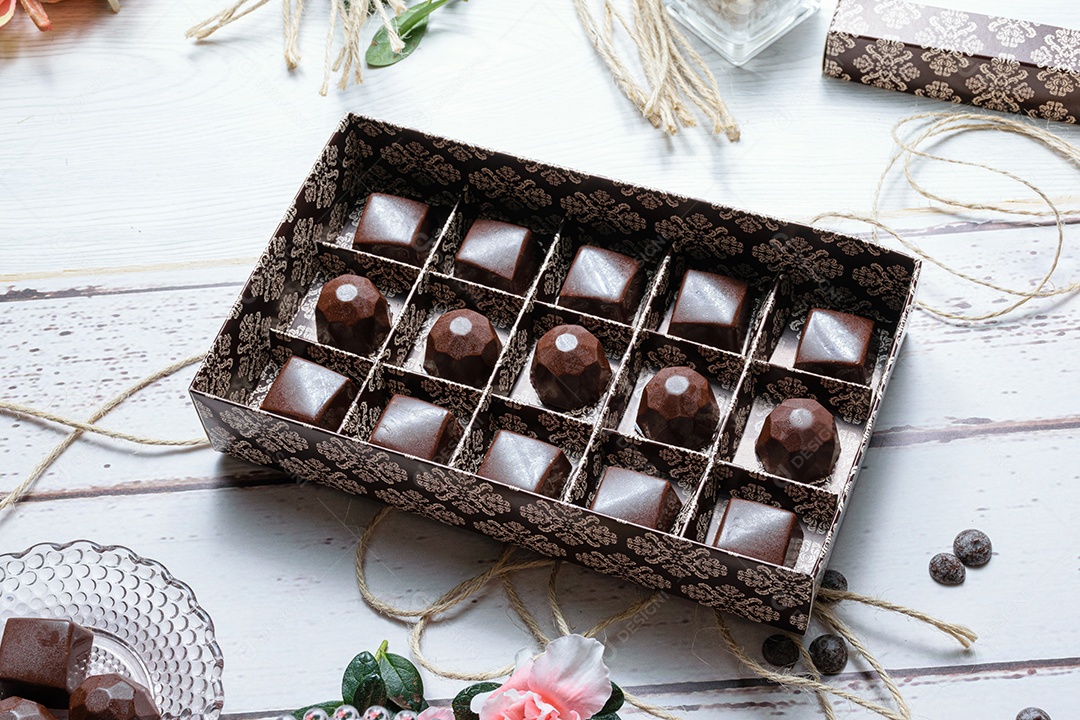 Caixa marrom com vários bombons de chocolate, em corda de barbante