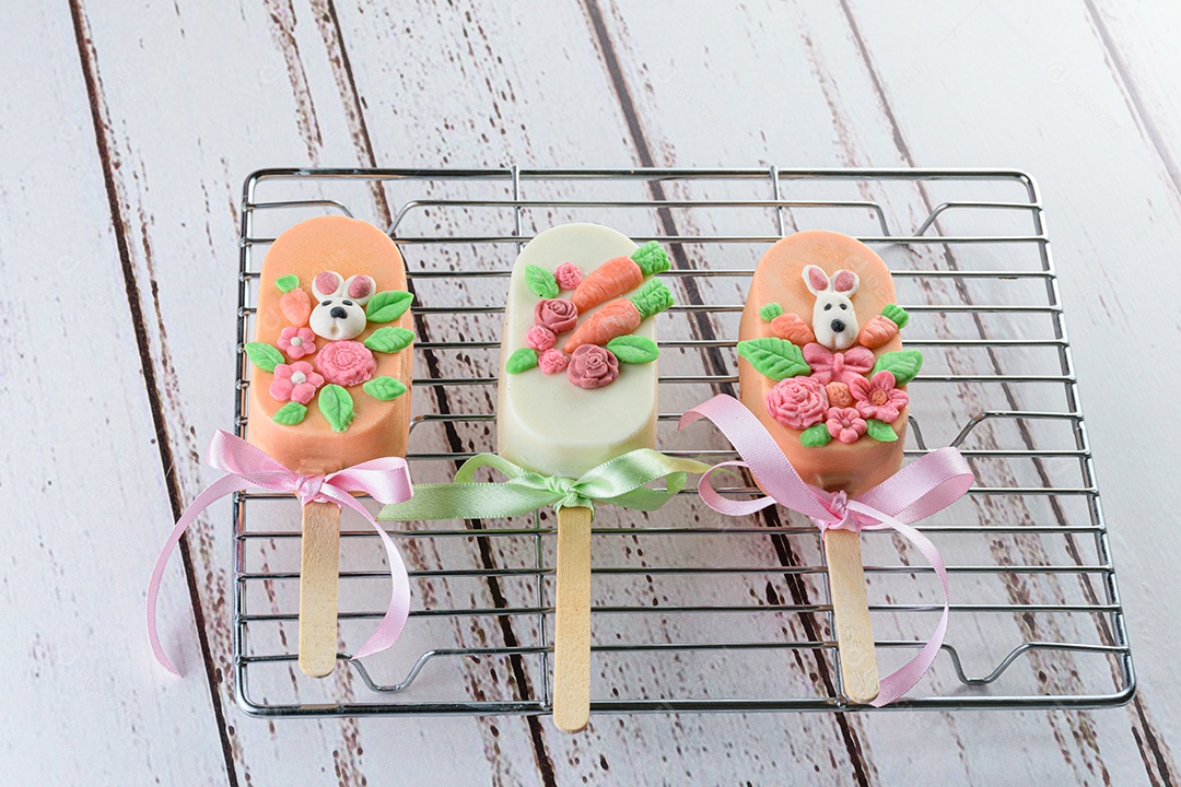 cakesicles de bolo de cenoura, decorado com coelho, flores e fita