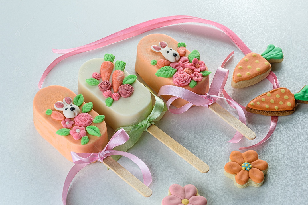 cakesicles de bolo de cenoura, decorados com coelho, flores e laço de fita.