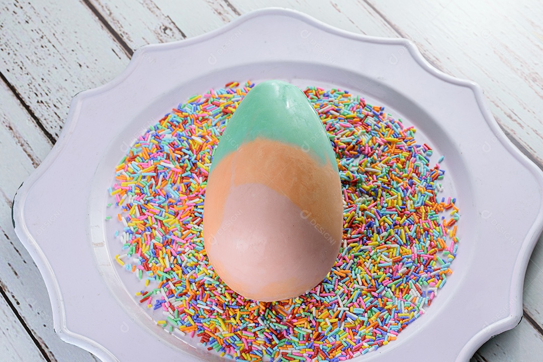 Ovo de Páscoa de chocolate branco pintado nas cores verde, laranja e rosa