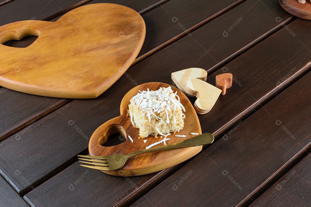 Bolo de coco com cobertura de coco ralado ao lado de um garfo de cobre