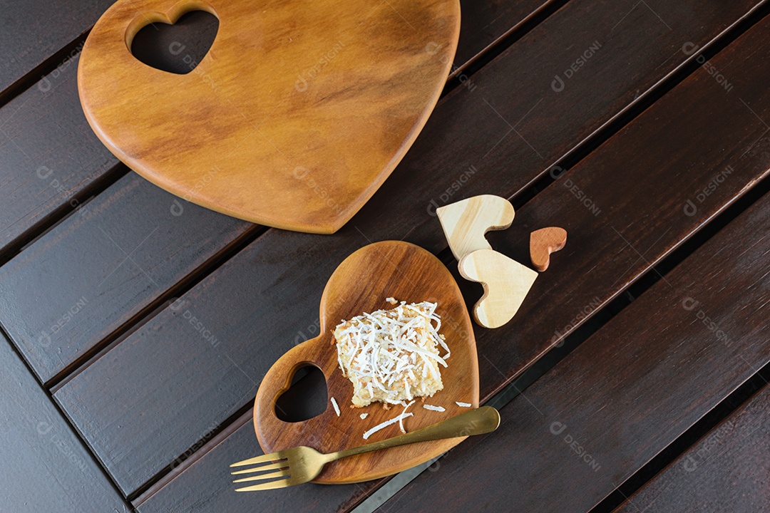 Bolo de coco com cobertura de coco ralado ao lado de um garfo de cobre