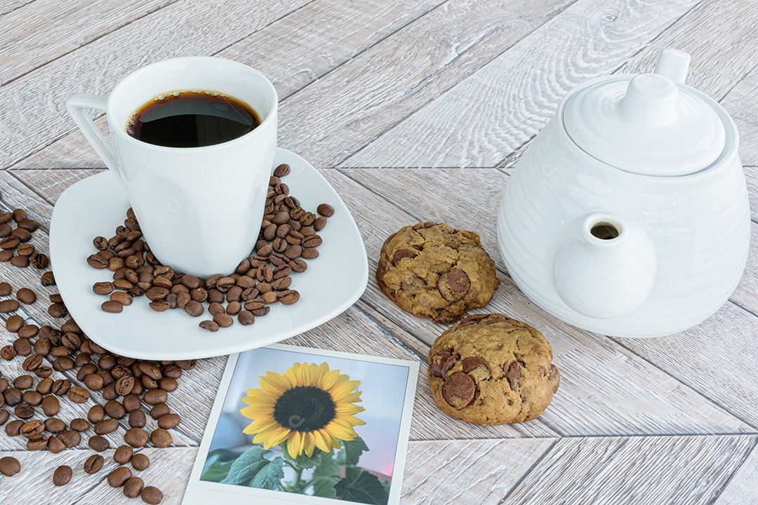 Dois biscoitos com gotas de chocolate rodeados por uma xícara de café