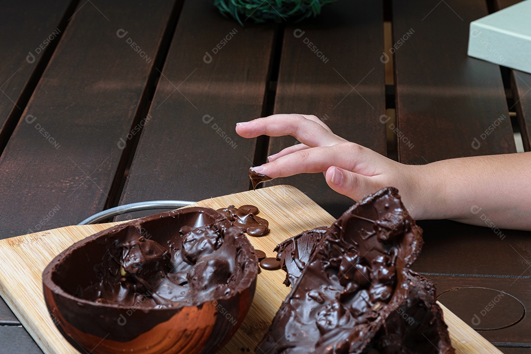 Criança derretendo o dedo com chocolate derretido