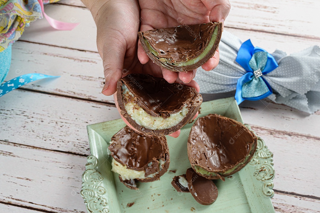 Mulher segurando duas metades de ovos de Páscoa de chocolate recheados