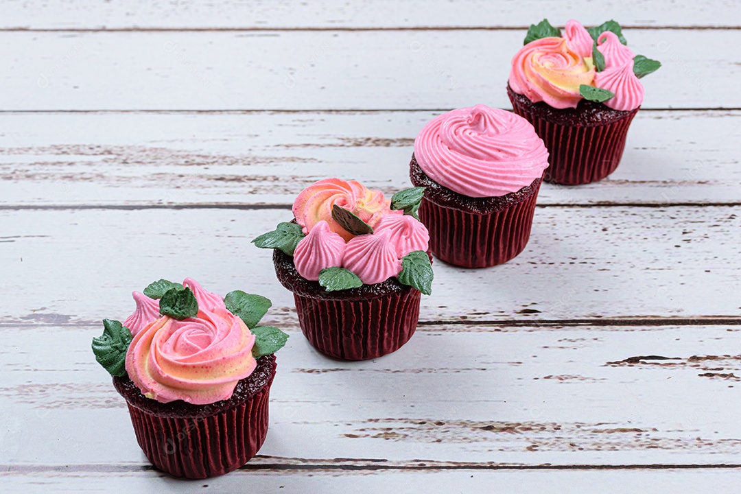 Quatro cupcakes red velvet cobertos com creme de manteiga rosa