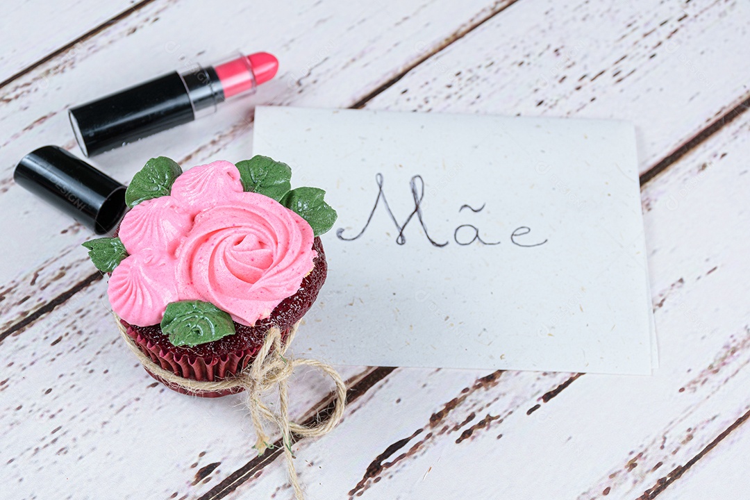 Cupcake red velvet com cobertura de creme de manteiga, ao lado de um batom