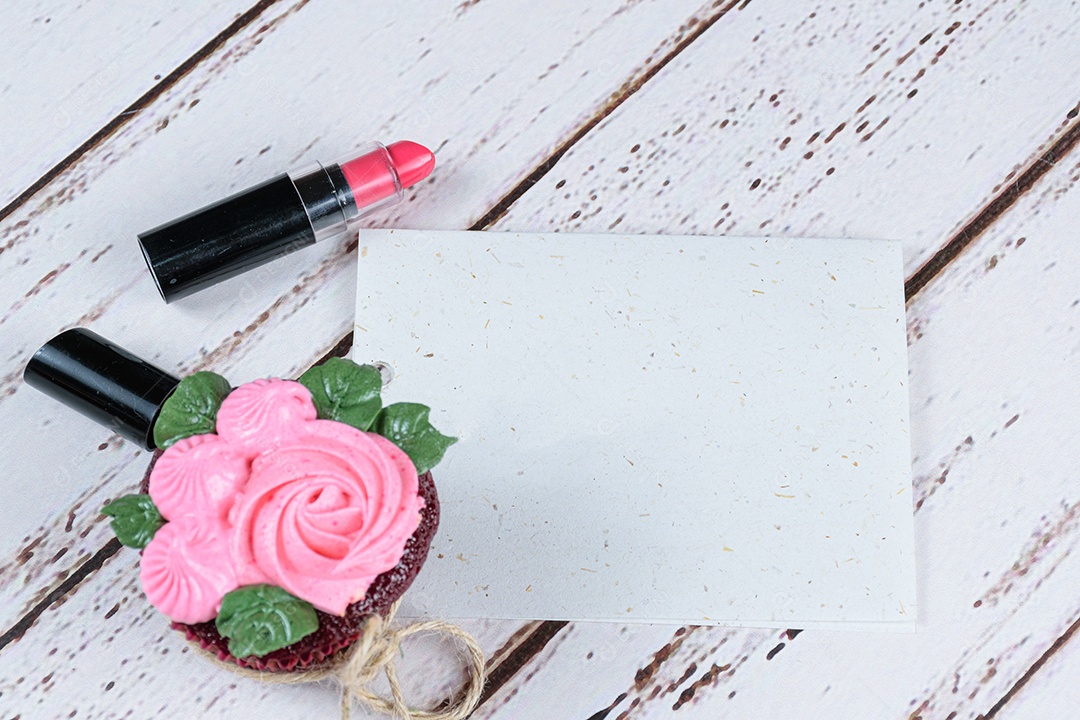 Bilhete em branco ao lado de um cupcake de veludo vermelho com creme de manteiga