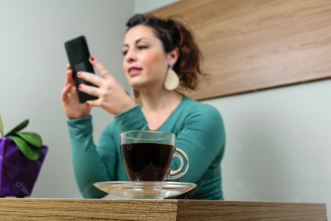 Em primeiro plano, close da xícara de café. No fundo desfocado