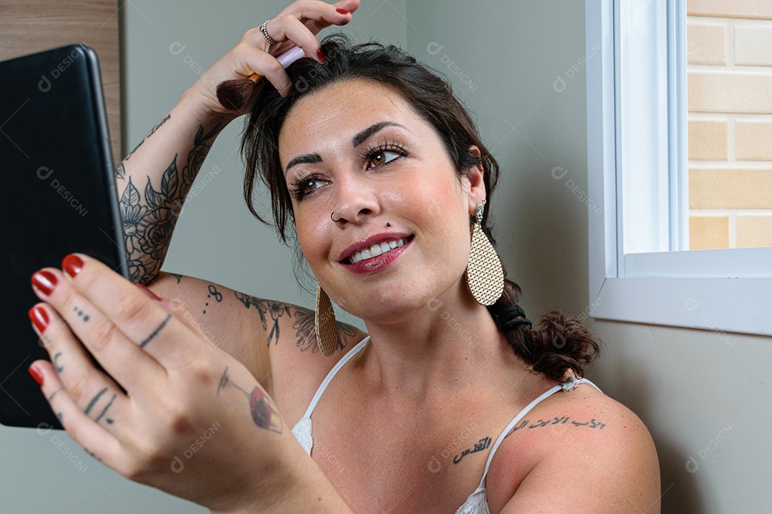 Mulher brasileira sorridente e tatuada ajeitando o cabelo