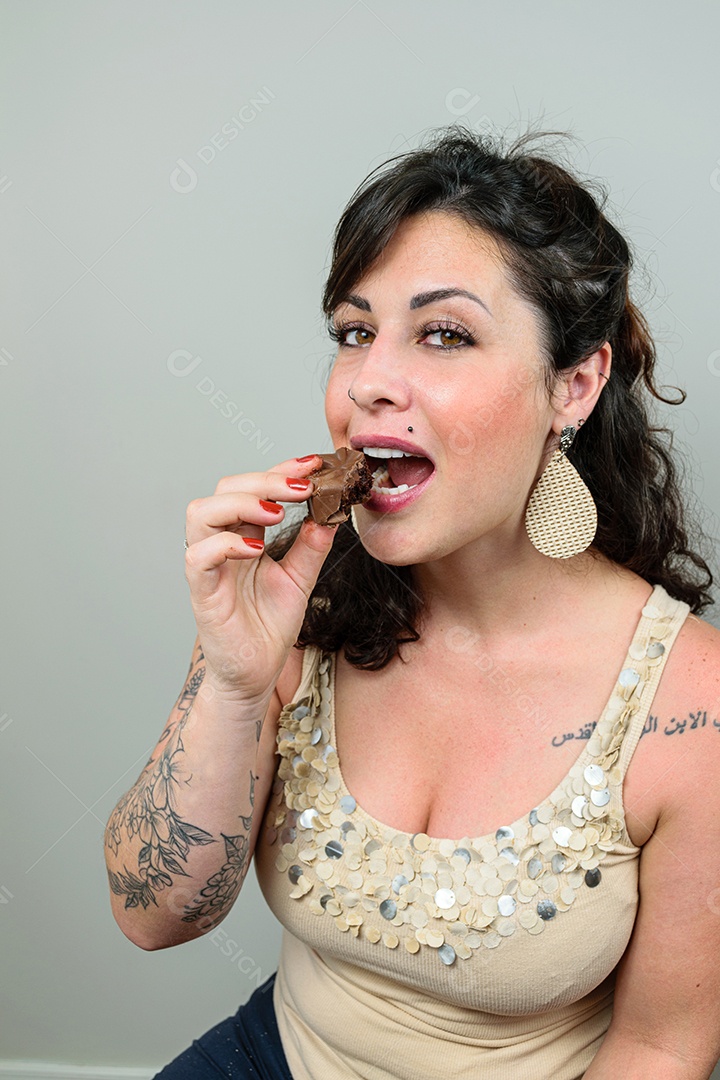 Mulher tatuada olhando para a câmera, pronta para comer um bolo brasileiro