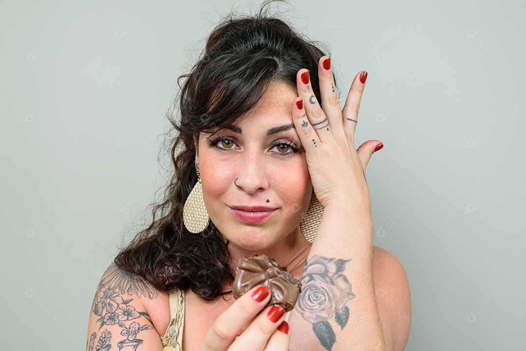 Mulher tatuada, olhando para a câmera, com a mão na cabeça