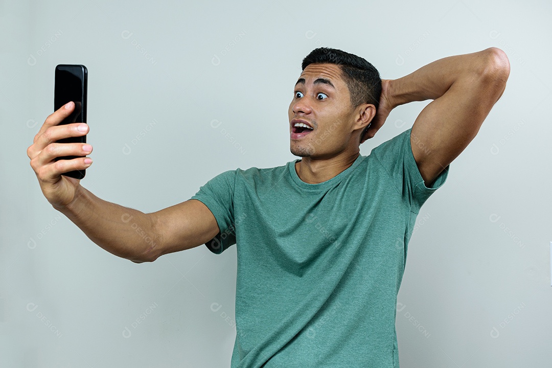 Jovem brasileiro, segurando e olhando para o smartphone