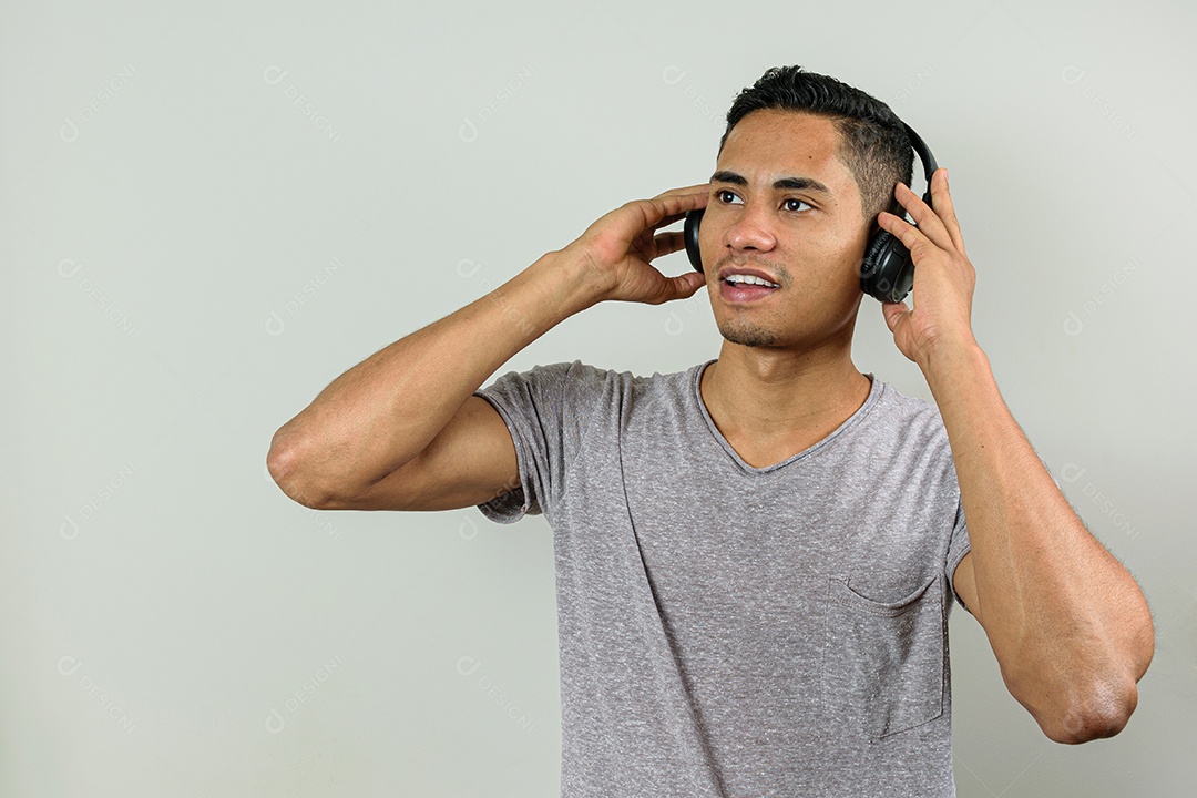 Brasileiro de 28 anos com as duas mãos segurando fone de ouvido sem fio