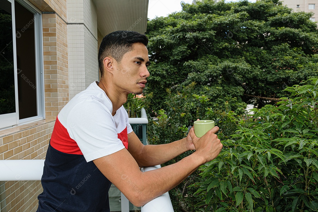 Jovem brasileiro segurando uma xícara de café, olhando para frente