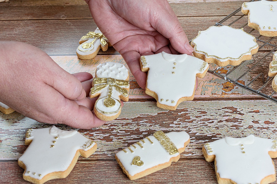 Confeiteiro organizando biscoitos amanteigados cobertos com glacê real.