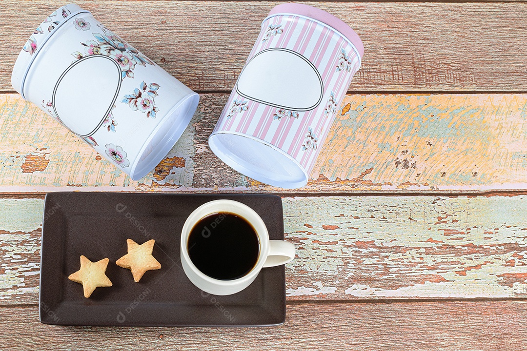 Biscoito amanteigado em forma de estrela ao lado de uma xícara de café e latas