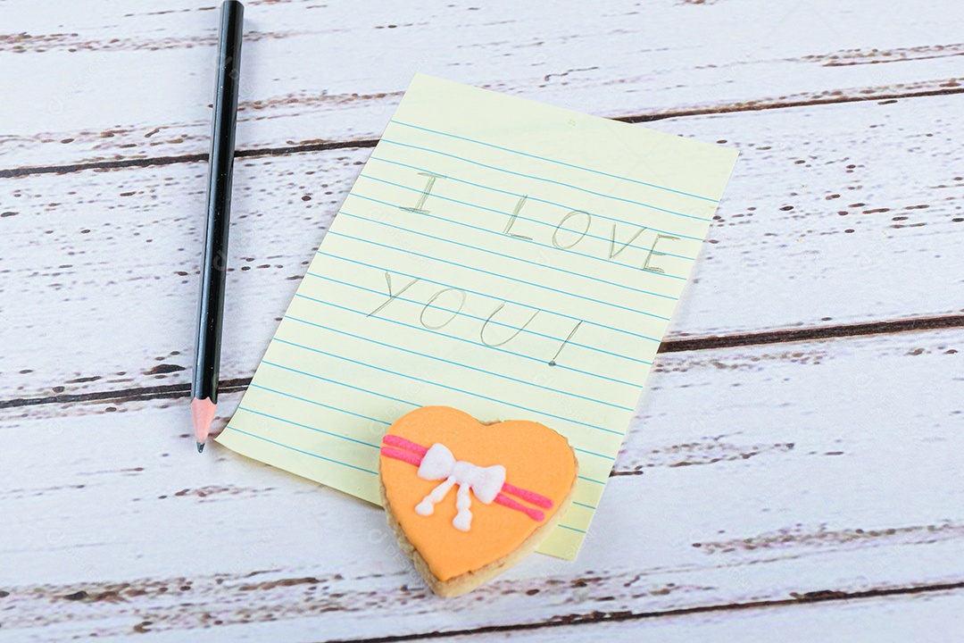Bloco de notas escrito eu te amo ao lado de um lápis e um biscoito