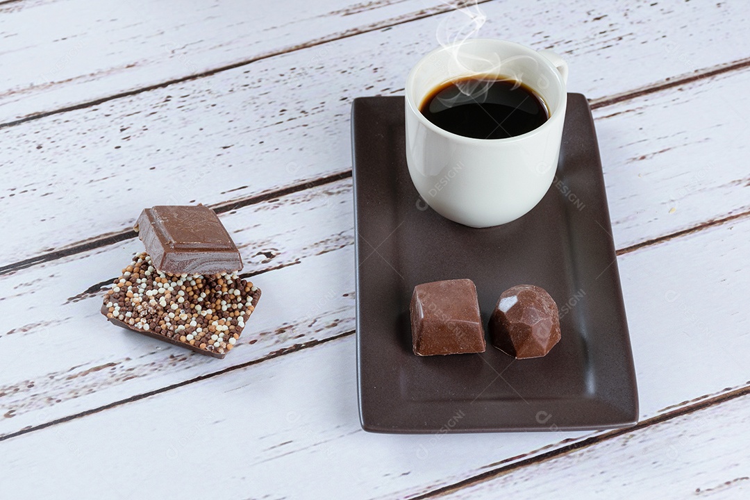 Barras de chocolate ao leite com granulado, ao lado de uma xícara de café