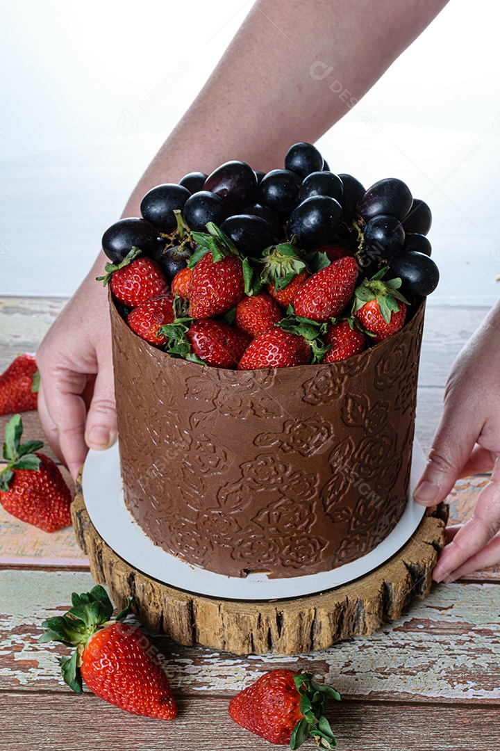 Confeiteiro colocando um bolo de chocolate sobre a mesa