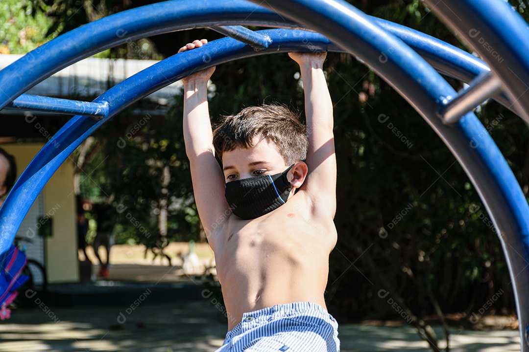 Detalhe de uma criança de 8 anos usando máscara balançando em um parque