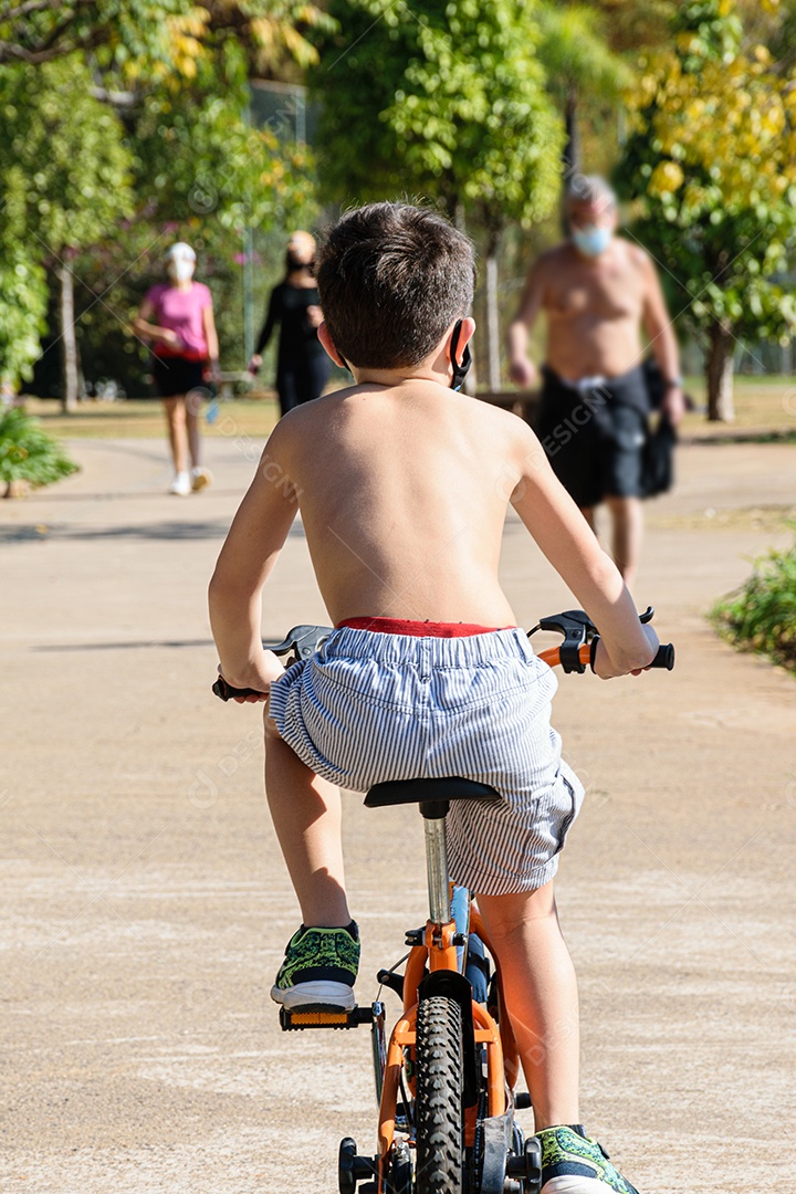 Criança de 8 anos, sem camisa, de costas andando de bicicleta