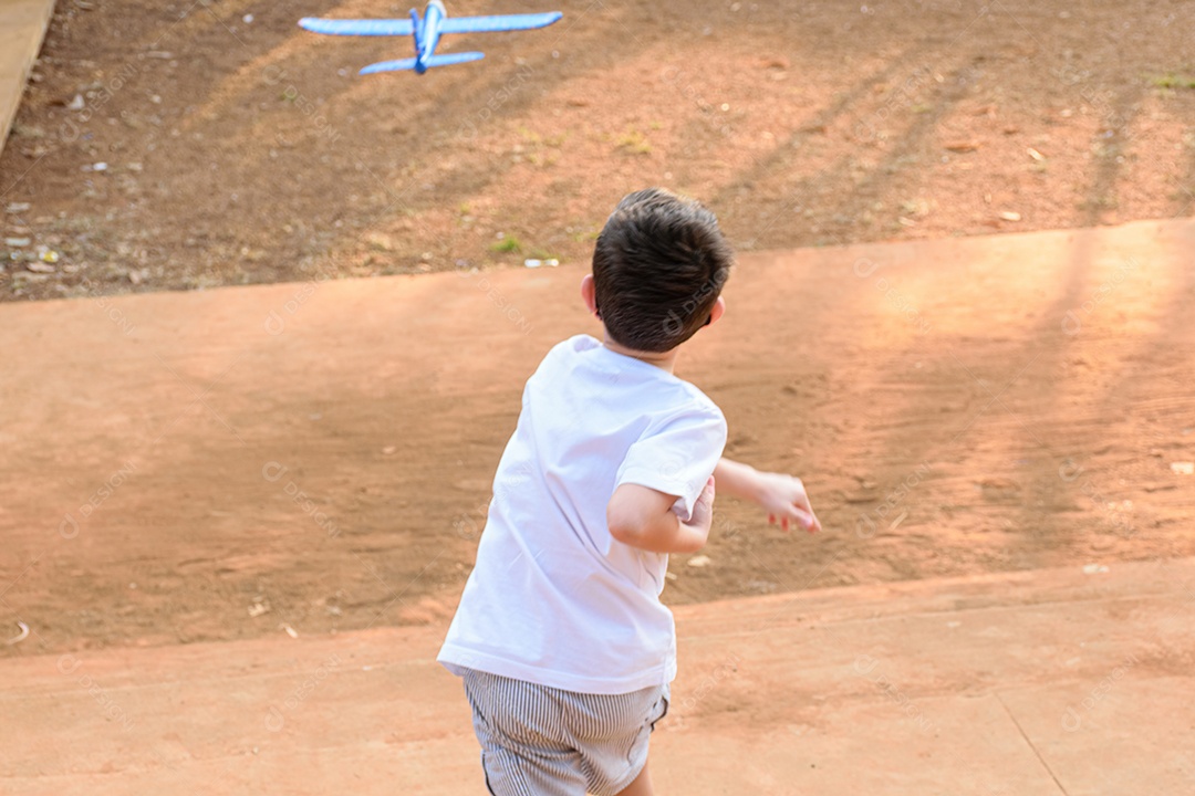 Criança de 8 anos, costas com costas, brincando com um avião de isopor