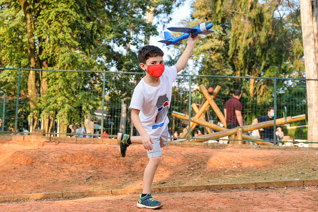 Criança de 8 anos, equilibrando-se em um pé, segurando seu avião de isopor azul