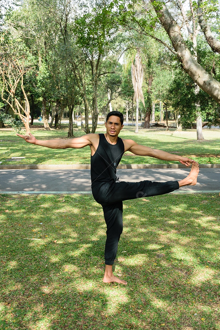 Jovem brasileiro praticando ioga em uma posição equilibrada