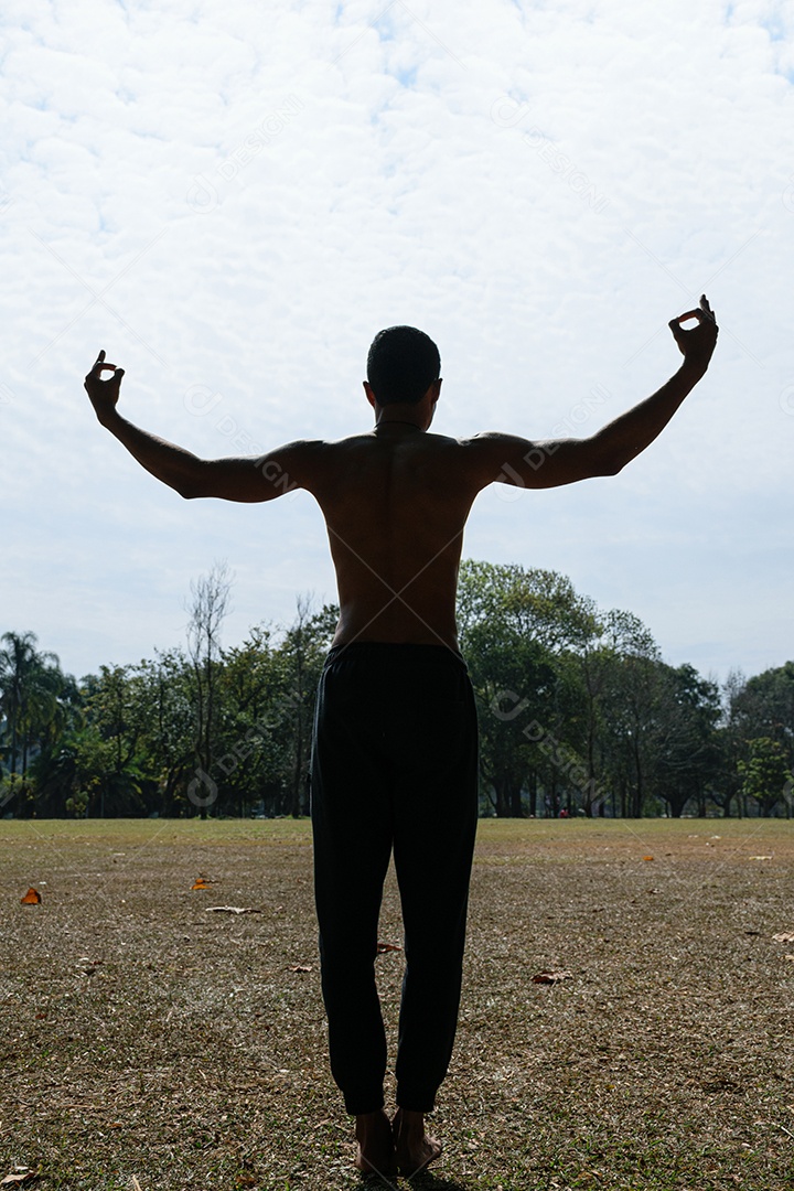 Silhueta de um jovem brasileiro sem camisa com as costas e os braços abertos