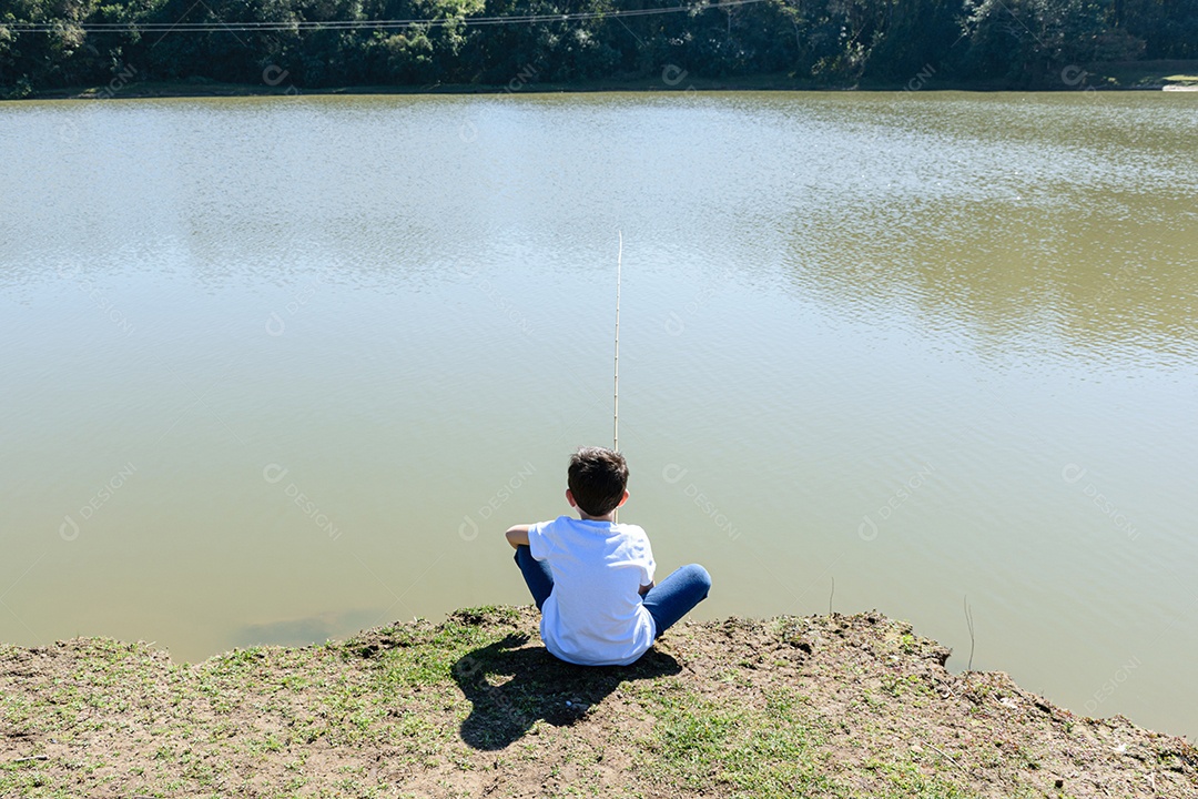 Criança brasileira de 8 anos, sentada de costas, pescando