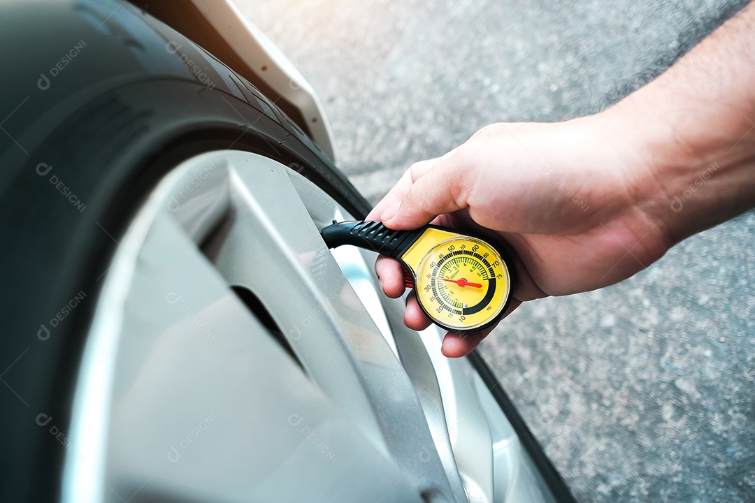 O motorista está medindo a pressão dos pneus com um pneu padrão