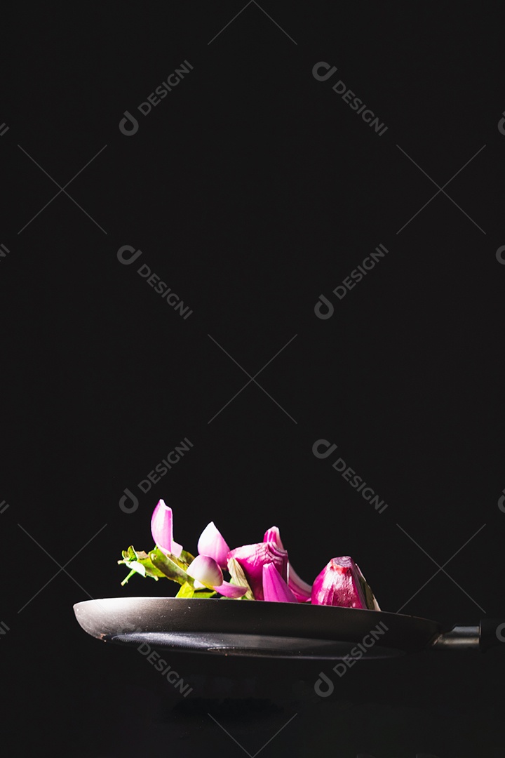 Frigideira jogando ingredientes como cebola roxa, queijo, manjericão