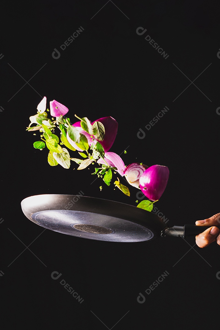 Frigideira jogando ingredientes como cebola roxa, queijo, manjericão