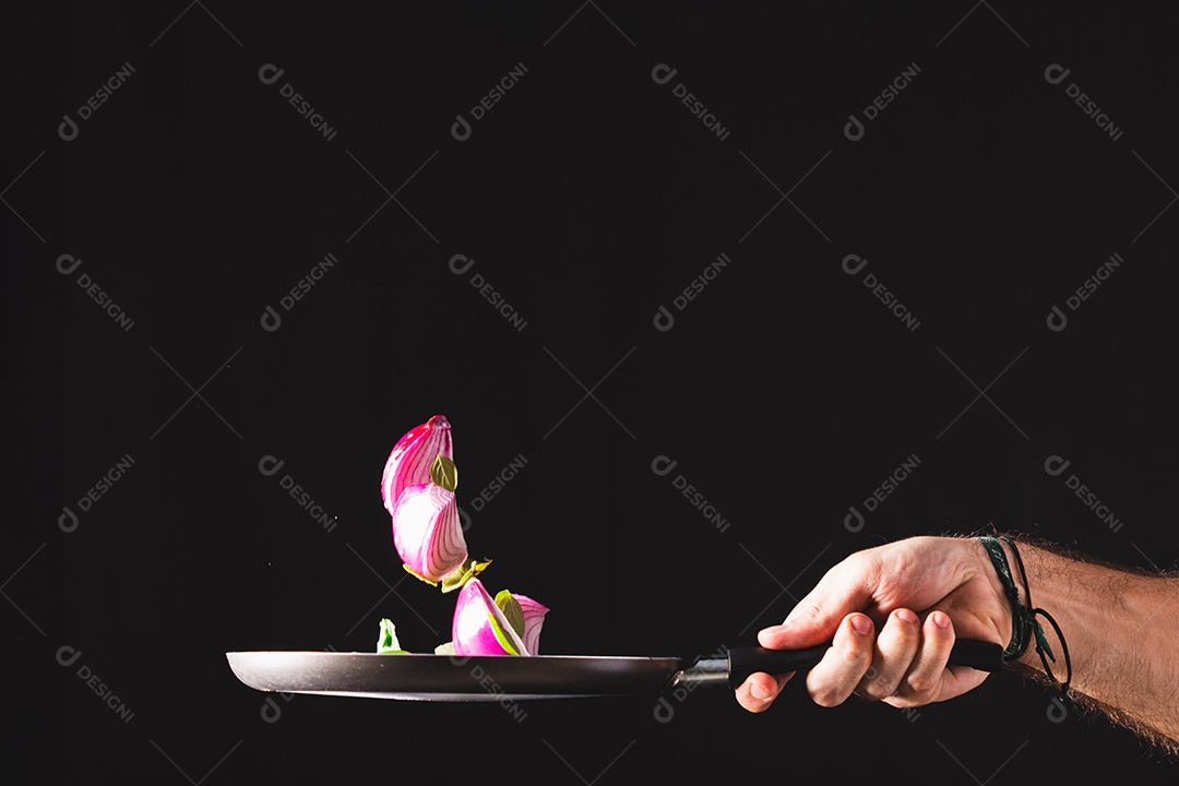 Frigideira jogando ingredientes como cebola roxa, queijo, manjericão