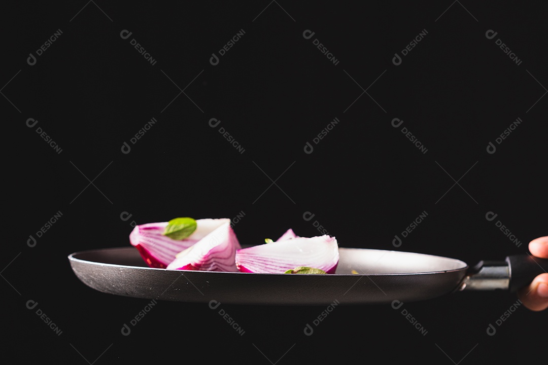 Frigideira jogando ingredientes como cebola roxa, queijo, manjericão