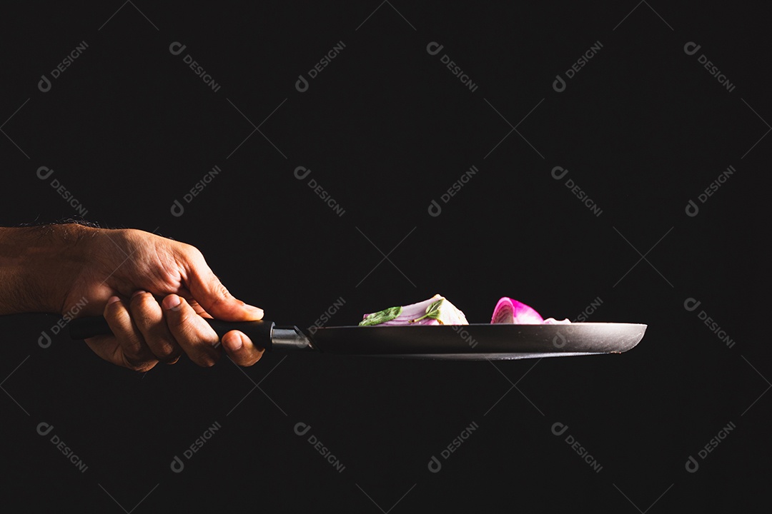 Frigideira jogando ingredientes como cebola roxa, queijo, manjericão