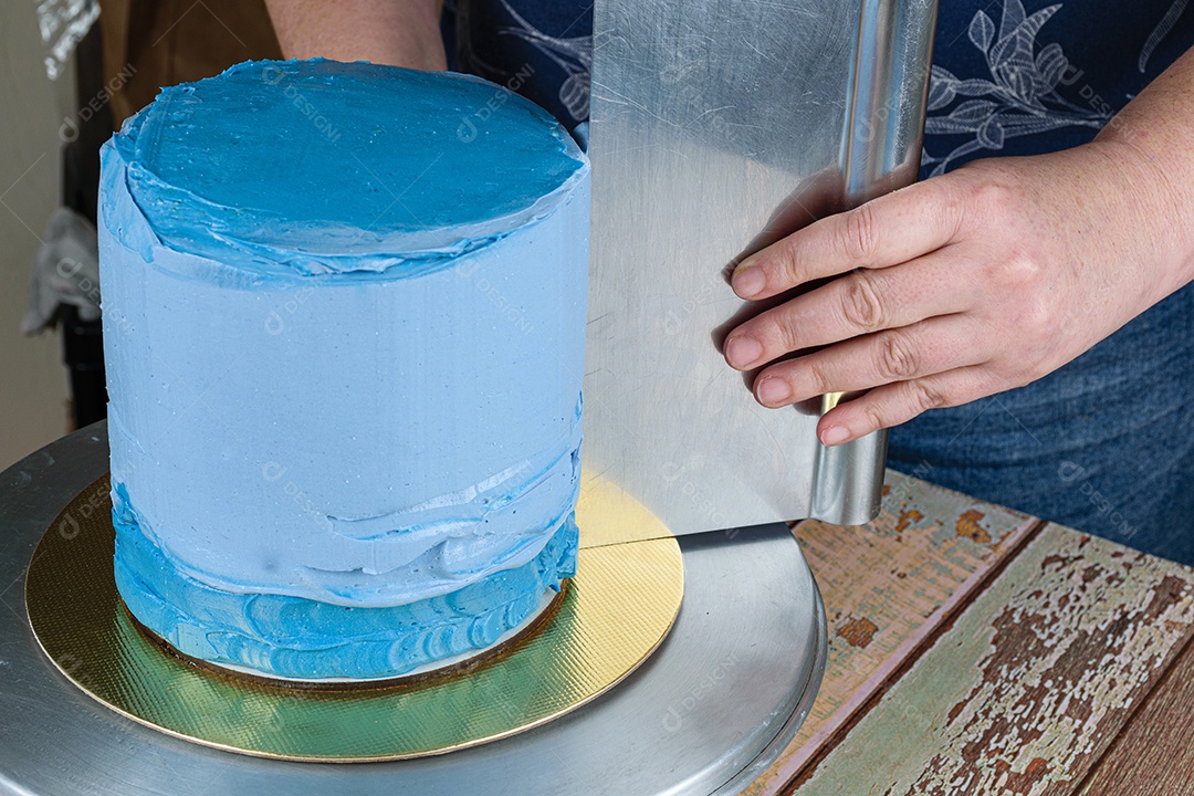 Confeiteiro usando uma espátula na lateral do bolo para espalhar