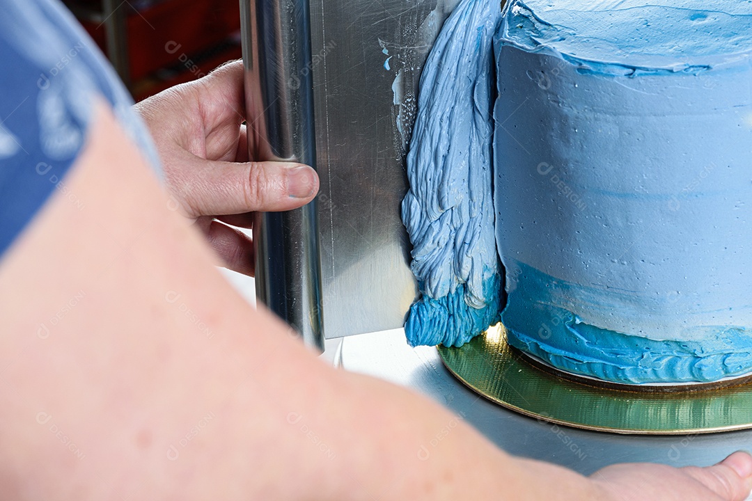 Detalhe de um confeiteiro usando uma espátula na lateral do bolo