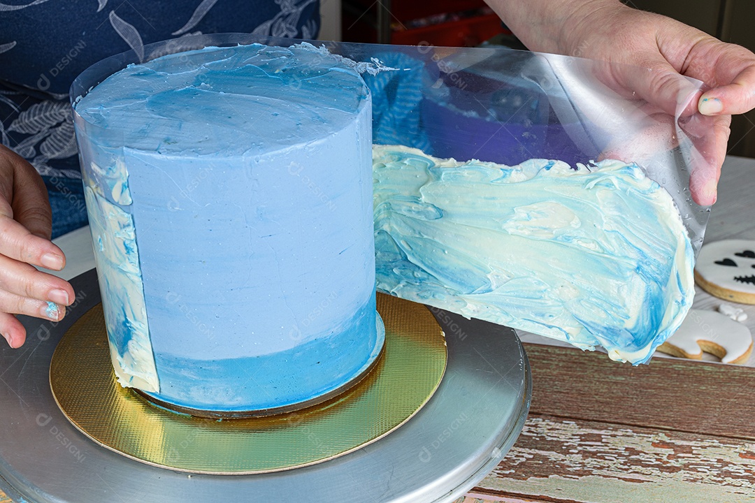 Confeiteiro colocando um acetato com glacê ao redor do bolo